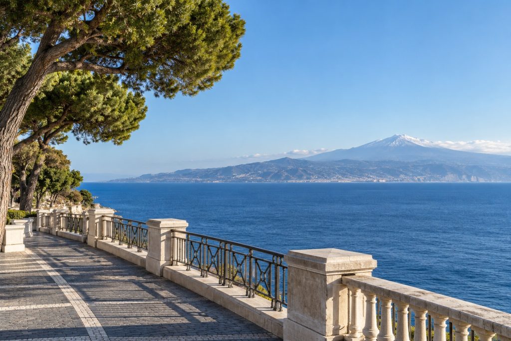 Il lungomare di Reggio Calabria con la balaustra e i pini, lo Stretto di Messina e la costa siciliana con l'Etna